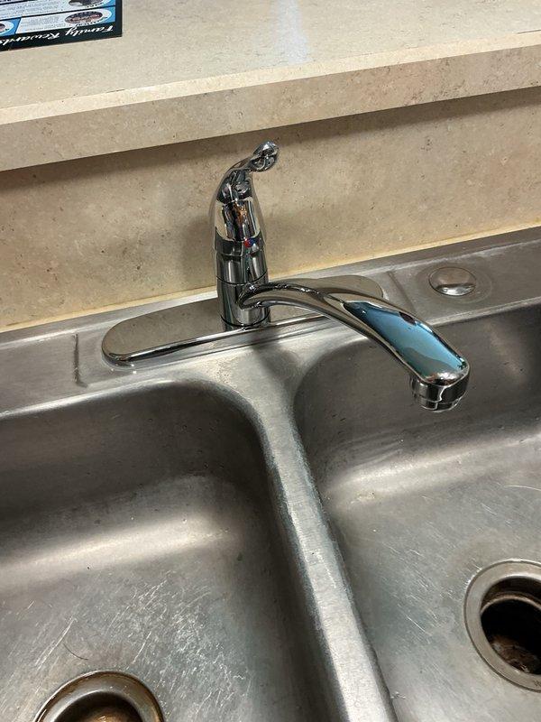 Responded to kitchen faucet with constant dripping issue. Upon assessment, presented repair versus replacement options to customer, who elected full replacement. Shut off water supply at under-sink valves, removed existing faucet assembly, and installed new single-handle chrome kitchen faucet on double-basin stainless steel sink. Reconnected supply lines to hot and cold water valves, restored water service, and performed leak test with successful results showing no leaks at connections or fixture.