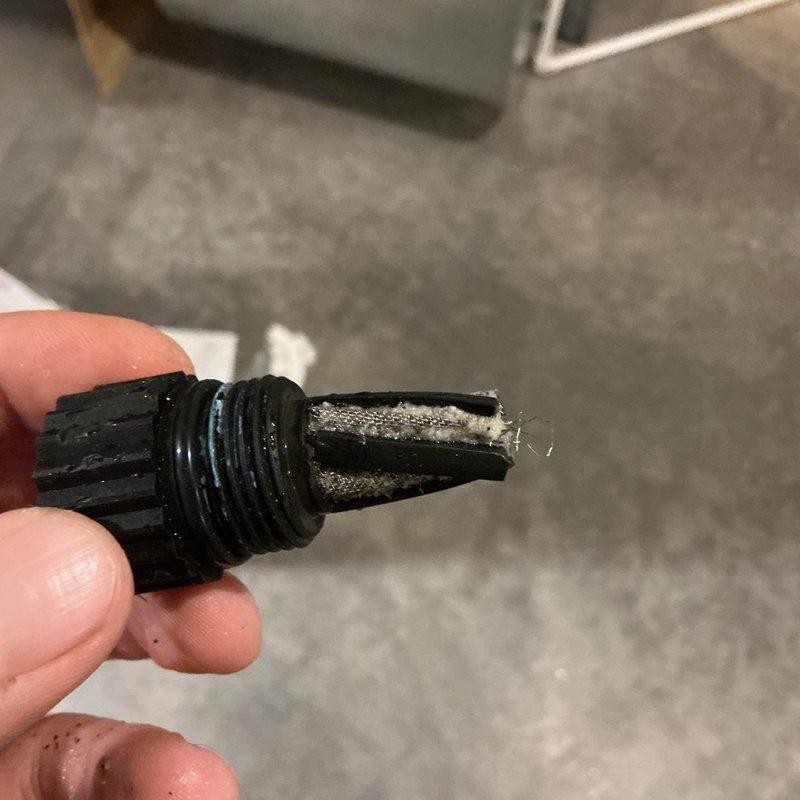 Responded to service call for low water pressure and no hot water at property with well water system. Upon inspection, diagnosed clogged and damaged inlet screen filter on cold water supply line to water heating system. Removed compromised filter component, cleaned debris from screen, and temporarily reinstalled cleaned filter to restore water flow and hot water functionality. Ordered replacement filter assembly for permanent repair. Documented existing Navien tankless water heater installation with associated plumbing connections, expansion tank, and gas line. Customer advised of temporary repair and pending replacement part installation.