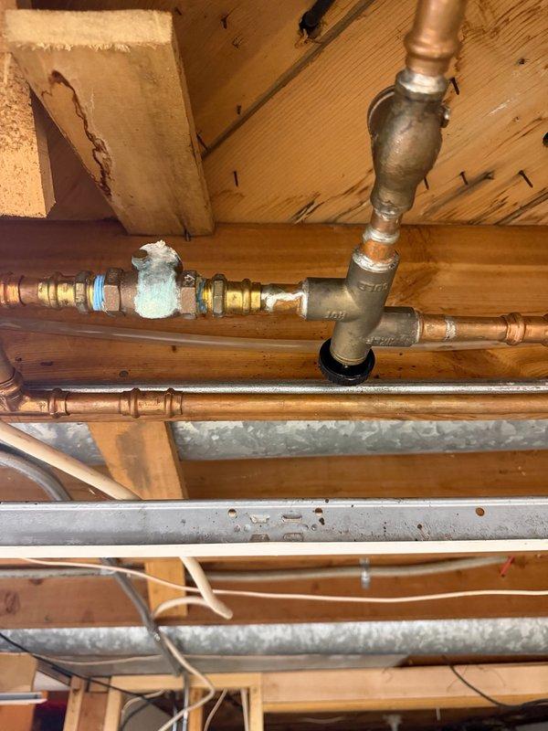 Responded to complaint of low to no hot water in main bathroom shower and water leaking in basement. Upon inspection, identified a damaged section of copper water pipe in the basement causing the leak and contributing to inadequate hot water delivery. Replaced the compromised pipe section with new copper piping, ensuring proper soldering and secure connections. Following repair, tested the system by running the shower continuously for 30 minutes to verify consistent hot water temperature and flow without fluctuation. System maintained steady hot water throughout the test period. Recommended follow-up evaluation for potential replacement of mixing valve and water heater to address underlying capacity concerns. Documented existing plumbing infrastructure with photos showing copper supply lines, shutoff valves, and basement mechanical space configuration.