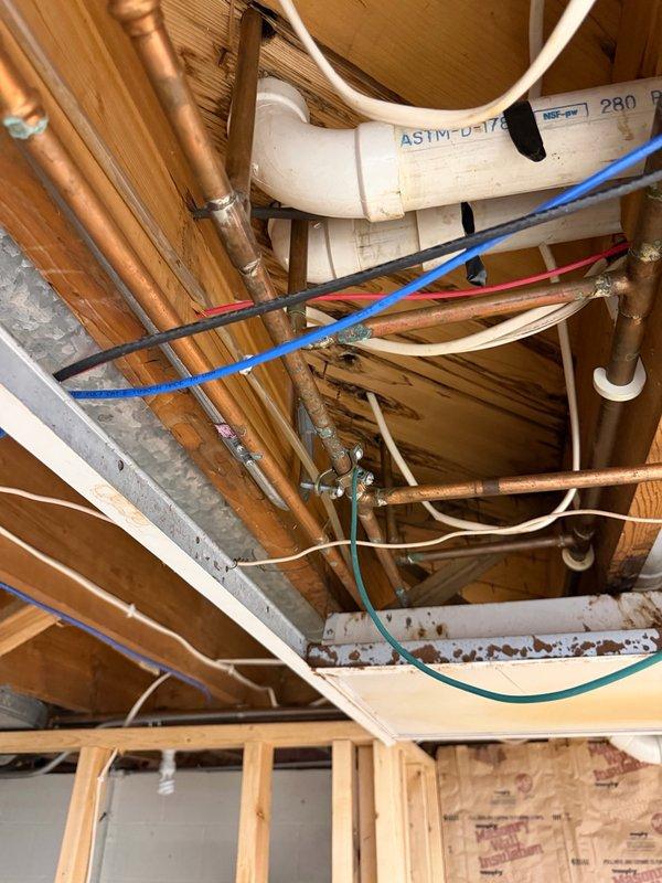Responded to complaint of low to no hot water in main bathroom shower and water leaking in basement. Upon inspection, identified a damaged section of copper water pipe in the basement causing the leak and contributing to inadequate hot water delivery. Replaced the compromised pipe section with new copper piping, ensuring proper soldering and secure connections. Following repair, tested the system by running the shower continuously for 30 minutes to verify consistent hot water temperature and flow without fluctuation. System maintained steady hot water throughout the test period. Recommended follow-up evaluation for potential replacement of mixing valve and water heater to address underlying capacity concerns. Documented existing plumbing infrastructure with photos showing copper supply lines, shutoff valves, and basement mechanical space configuration.