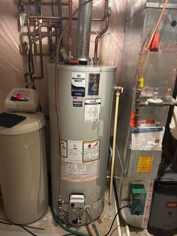 Responded to callback regarding recently installed Bradford White water heater with inaccessible temperature and pressure relief valve. Upon arrival, confirmed relief valve handle was positioned too close to furnace return duct, preventing proper operation and testing. Drained water heater completely and repositioned unit several inches away from ductwork to provide adequate clearance for relief valve actuation. Refilled tank, purged air from system, and relit pilot light. Verified proper burner operation and confirmed relief valve handle now accessible for routine testing and maintenance. System tested and left in full operating condition with no issues found.