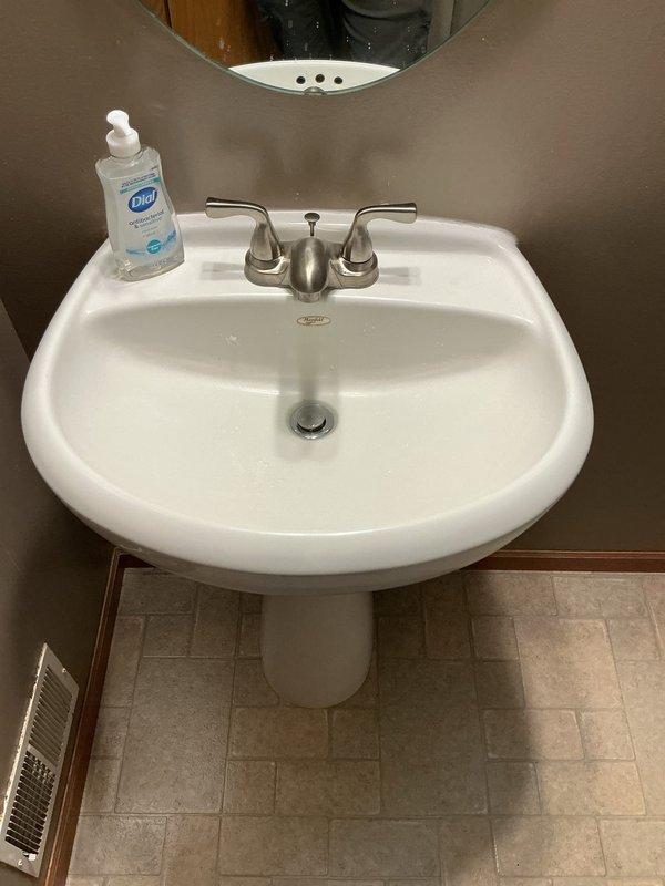 Responded to warranty callback for persistent water leak at pedestal sink installation. Upon inspection, discovered water was not leaking from supply line connections but rather dripping onto the faucet assembly and traveling down the pull mechanism, creating the appearance of a plumbing leak. Verified all water supply connections and shut-off valves were secure and functioning properly with no active leaks present. Determined the issue originated from the faucet unit itself rather than the plumbing installation. Documented findings with photographs showing supply line connections and overall sink assembly. Provided proposal for faucet replacement to resolve the ongoing dripping issue.