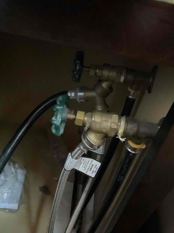 Responded to report of slow drip in laundry room plumbing. Upon arrival, conducted thorough visual inspection of all accessible plumbing connections, supply lines, and shut-off valves in the laundry area. Customer reported operating the shut-off valve prior to service call, which resulted in additional leaking at the valve assembly. Inspected brass shut-off valves, compression fittings, and flexible braided supply lines underneath counter area. No active leaks were observed during inspection. All plumbing connections, including ball valves with handles and flexible supply lines, appeared secure and in functional condition at time of service. Documented plumbing assembly configuration with photos showing valve connections and supply line routing for future reference.