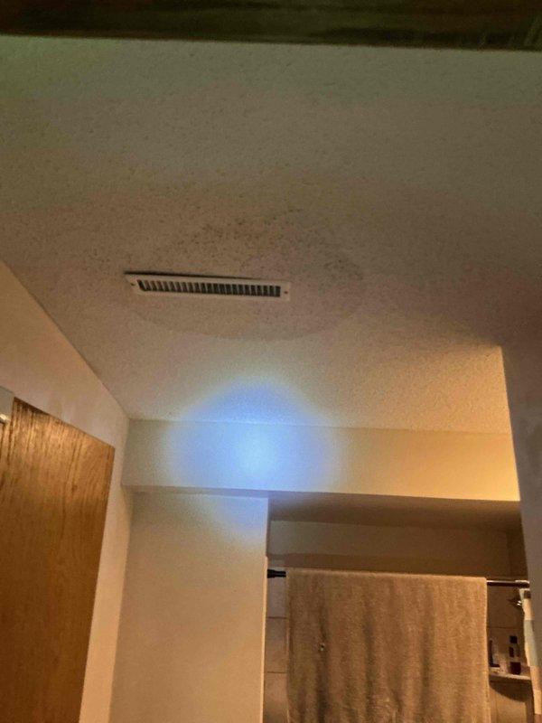 Responded to emergency water leak originating from upstairs bathroom penetrating ceiling below. Upon arrival, water supply had been shut off by occupant. Conducted visual inspection of affected areas including ceiling damage and upstairs bathroom. Identified phantom leak requiring specialized detection equipment. Coordinated with third-party leak detection service to locate source of non-visible water intrusion within bathroom floor assembly and subfloor system. Documented damage to ceiling and bathroom conditions with photographs for restoration purposes.