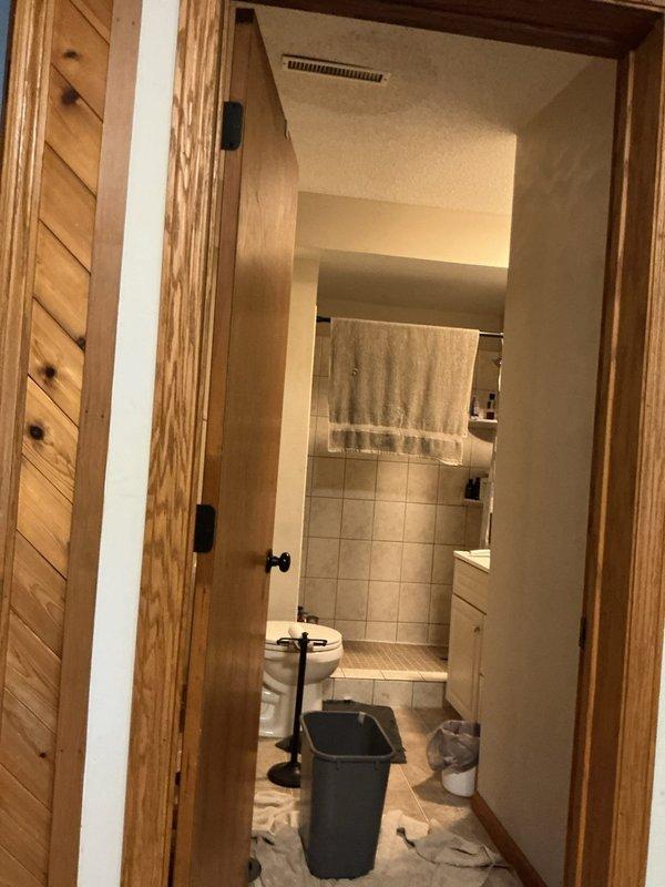 Responded to emergency water leak originating from upstairs bathroom penetrating ceiling below. Upon arrival, water supply had been shut off by occupant. Conducted visual inspection of affected areas including ceiling damage and upstairs bathroom. Identified phantom leak requiring specialized detection equipment. Coordinated with third-party leak detection service to locate source of non-visible water intrusion within bathroom floor assembly and subfloor system. Documented damage to ceiling and bathroom conditions with photographs for restoration purposes.
