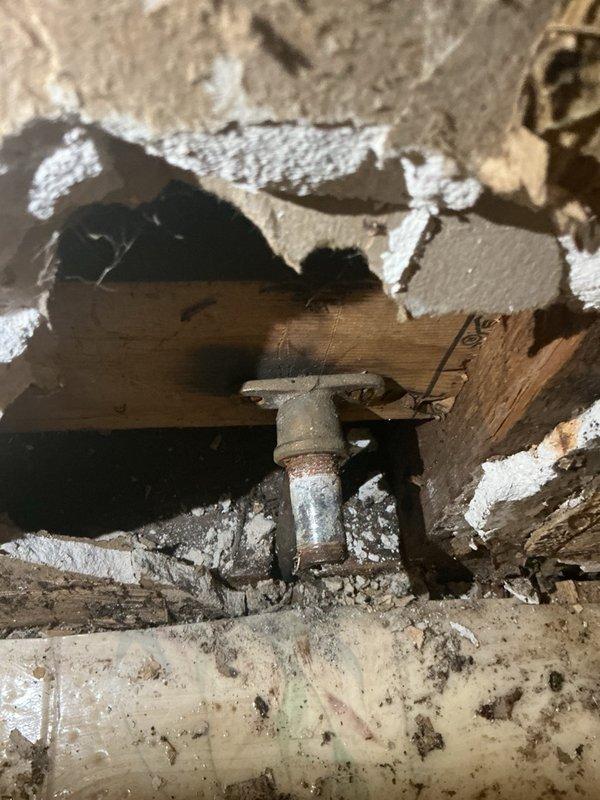# Plumbing Service - Broken Toilet Stub Out

Responded to service call for leaking pipe in bathroom. Upon arrival, performed thorough inspection of the affected area and identified a broken toilet stub out as the source of the water leak. The toilet flange connection had fractured, with the stub out pipe broken off at the structural framing level.

Documented extensive water damage to surrounding wall surfaces, including deteriorated drywall, delaminated paint layers, and compromised plaster materials in the corner section where walls meet. Inspection revealed the damaged PVC plumbing line running through the wall cavity behind compromised surface materials. Access opening exposed wooden structural framing and the full extent of the broken pipe connection.

Provided comprehensive assessment of repair requirements, including removal of damaged wall materials, replacement of broken toilet stub out fitting, proper reconnection to existing plumbing line, and restoration of wall surfaces. R
