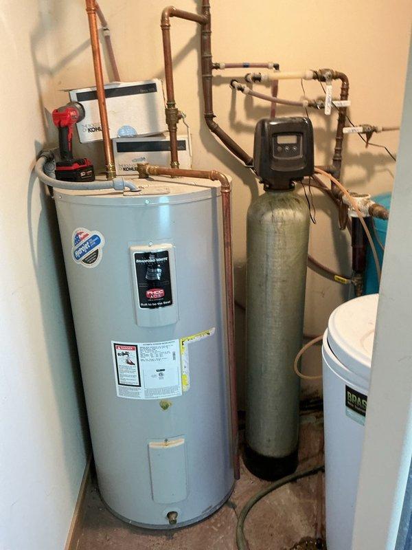 Responded to service call for malfunctioning water softener displaying error code and causing rust staining in water supply. Upon inspection, determined the softener control head was mechanically jammed and inoperable. Documented existing system configuration including water heater, softener tank, and brine tank connections. Referred customer to sales department for control head replacement or system upgrade options due to severity of mechanical failure.