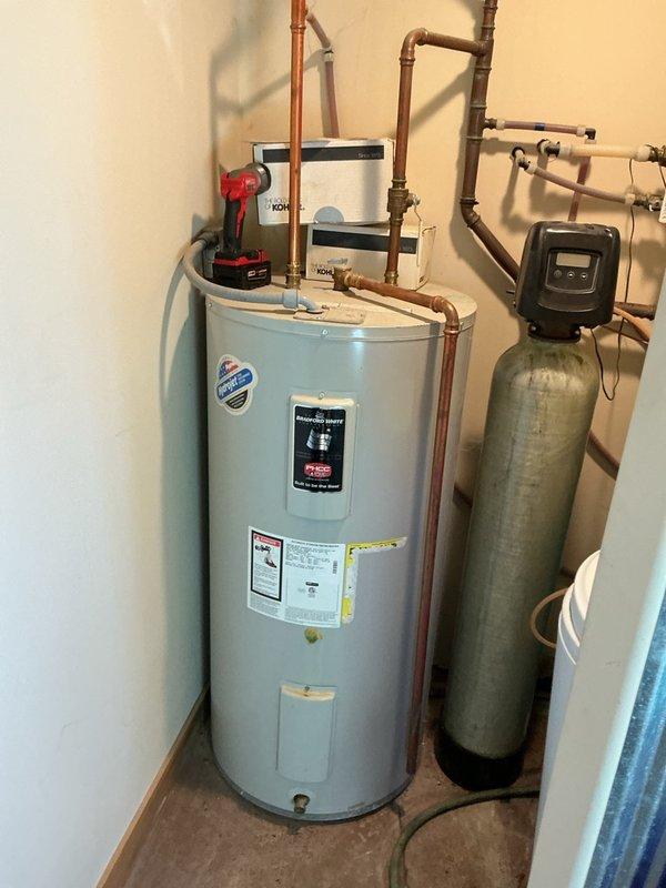 Responded to service call for malfunctioning water softener displaying error code and causing rust staining in water supply. Upon inspection, determined the softener control head was mechanically jammed and inoperable. Documented existing system configuration including water heater, softener tank, and brine tank connections. Referred customer to sales department for control head replacement or system upgrade options due to severity of mechanical failure.