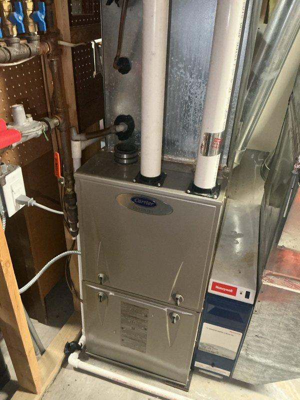 Performed annual heating maintenance on a 14-year-old Carrier furnace and identified critical safety concerns requiring immediate attention. Upon inspection, discovered significant rusting in the combustion cabinet, a cracked inducer draft motor housing leaking condensation, and evidence of combustion gas leakage on both primary and secondary heat exchangers with visible condensation and exhaust marks. Due to the likelihood of carbon monoxide leakage and the extent of deterioration, recommended complete furnace replacement and scheduled an estimate appointment for the customer.