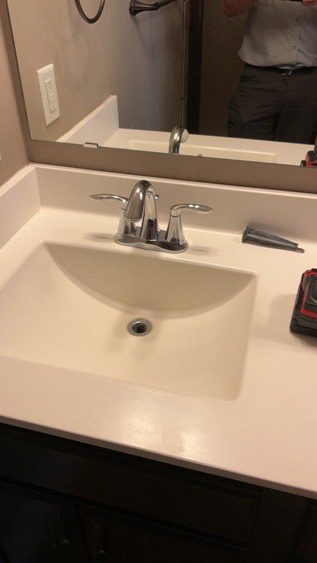 Responded to service call for master bathroom lavatory faucet with stiff operation and malfunctioning drain plug. Assessed center-set chrome faucet with dual lever handles and inspected under-cabinet plumbing connections including P-trap and supply lines. Provided estimates for faucet replacement due to worn internal components affecting handle operation and integrated pop-up drain assembly.