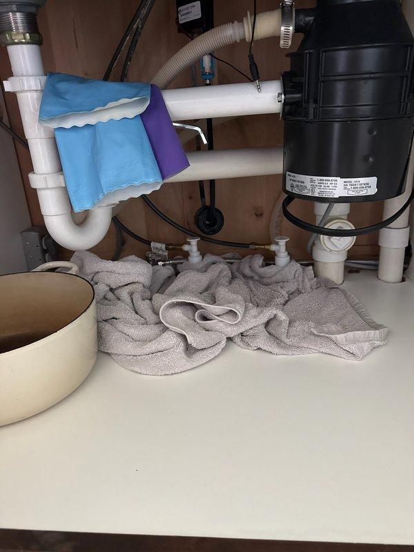Responded to service call for kitchen sink and shower head leaks. Inspected kitchen sink plumbing and discovered the faucet mounting clip was improperly seated, causing water leakage under the cabinet. Repositioned and secured the clip to manufacturer specifications, resolving the kitchen sink leak. Addressed loose shower head by removing existing connection, applying new thread tape and pipe dope, and properly tightening to eliminate leak. During inspection, identified active leak on 10-year-old 50-gallon AO Smith water heater with visible corrosion on lower tank section. Documented water heater condition with photos for customer review and future service planning.