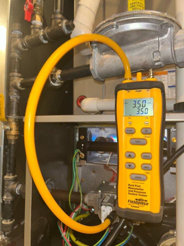 Completed comprehensive furnace tune-up inspection on residential heating system. Performed full diagnostic evaluation including thermostat operation, air filter condition, blower assembly, burner and heat exchanger compartment, inducer operation, ignition system, flame sensor, safety controls, electrical components, condensate drain, and temperature rise measurements. Utilized dual port manometer to verify gas pressure readings, which measured within manufacturer specifications at 350 and 358 on digital display. All system components found operating within normal parameters with no mechanical deficiencies or safety concerns identified. Documented equipment make, model, and serial number information with photographs. System verified to be functioning properly and safely at time of inspection.