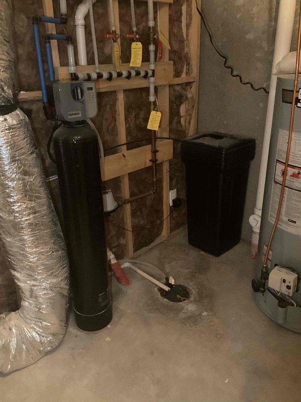 Completed comprehensive plumbing inspection of residential property including basement mechanical room and bathroom facilities. Inspected water treatment system consisting of green filtration tank and black brine tank, verified proper operation of water softener controls and PEX manifold distribution system, examined water heater connections and supply lines for leaks or corrosion, and assessed all visible plumbing infrastructure in utility area. Evaluated bathroom plumbing fixtures including toilet with bidet attachment, vanity connections, and shower/tub assembly to ensure proper function and identify any potential issues requiring attention.