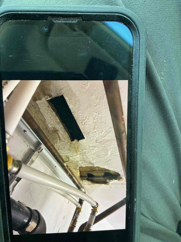 Responded to reported water leak in downstairs closet of multi-unit residential property. Upon arrival, inspected affected area and found no active water present. Accessed ceiling cavity via ladder and removed access panel to examine upstairs kitchen plumbing lines serving upper apartment unit. Conducted leak testing on all accessible piping and fixtures in upstairs kitchen with no leaks detected. Inspection revealed evidence of previous water damage to ceiling materials from prior repair work, but no current moisture or active dripping observed. Tenant reported leak occurs only during rainfall, suggesting potential roof or exterior water intrusion rather than plumbing system failure. Documented conditions with photographs showing ceiling access point, exposed framing, and water-stained materials. Additionally performed inspection of downstairs toilet per request and provided replacement proposal using owner-supplied fixture. No immediate plumbing repairs required at this time; recomme
