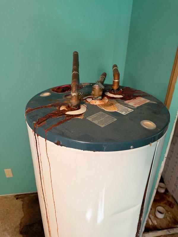 Responded to water heater failure with significant leakage that caused floor damage in utility area. Successfully removed failed tanked water heater unit exhibiting extensive corrosion on copper supply lines and rust staining on tank body, indicating prolonged leak condition. Disconnected water supply connections, drained remaining water from tank, and safely extracted unit from installation location. Assessed and documented water damage to concrete floor surface caused by leaking unit. Site prepared for future water heater installation to be scheduled at later date.