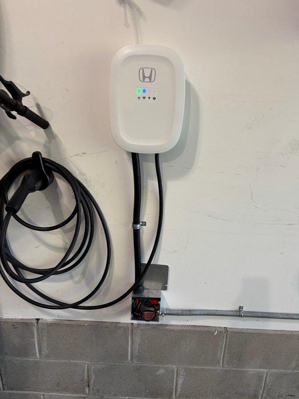 Installed customer-supplied EV charger in garage adjacent to existing 200amp Square D HOM electrical panel. Ran 6 THHN conductors through surface-mounted EMT conduit to junction box and hardwired charger with 60amp fusing for 48amp output capability. Completed programming and setup of charging unit, passed virtual inspection under permit ELE2609-00232, and noted homeowner preference for ChargePoint unit over Electrum charger for potential future consideration.