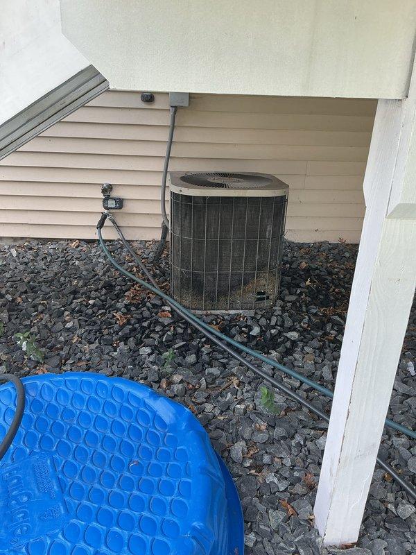 Completed annual air conditioning tuneup and inspection on residential outdoor condensing unit. During inspection, discovered significant damage to condenser coils including a large hole caused by dog urine corrosion. Condenser fan motor exhibited hard-start condition requiring manual assistance to initiate operation. Overall coil condition is severely deteriorated. Recommended either replacing the condenser fan motor as a short-term repair or considering full AC unit replacement due to extent of coil damage and age of equipment.