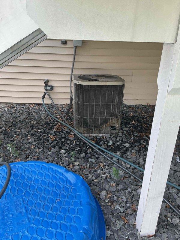 Completed annual air conditioning tuneup and inspection on residential outdoor condensing unit. During inspection, discovered significant damage to condenser coils including a large hole caused by dog urine corrosion. Condenser fan motor exhibited hard-start condition requiring manual assistance to initiate operation. Overall coil condition is severely deteriorated. Recommended either replacing the condenser fan motor as a short-term repair or considering full AC unit replacement due to extent of coil damage and age of equipment.