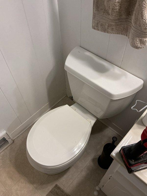 Responded to service call for leaking toilet with failed wax ring seal and inoperative shut-off valve. Upon inspection, identified leaking bolts and gaskets at the base of the toilet fixture. Assessed condition of mounting hardware and sealing components, noting corrosion and deterioration around the flange area. Documented existing conditions and provided estimate for complete toilet replacement due to extent of seal failure and compromised mounting system.