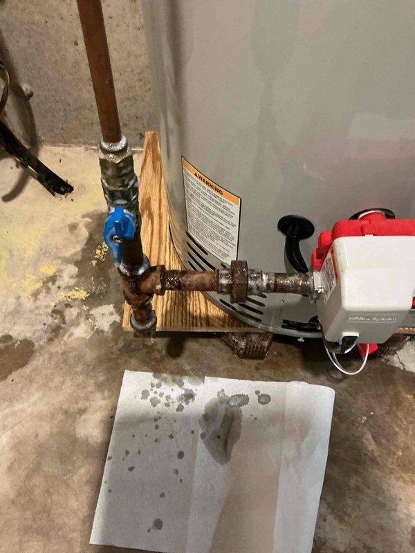 Responded to a leaking 40-gallon LP power vent Bradford White water heater with water discharge from the bottom of the unit. Confirmed the unit was still under warranty coverage and assessed replacement options, noting that 50-gallon units were available on the service vehicle. Provided technical assistance with the water heater replacement process, including disconnection of copper supply lines, removal of the failed unit from wooden blocking supports, and preparation of the installation area in the basement utility space where the pressure tank and related plumbing infrastructure are located.