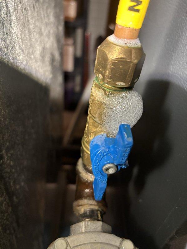 Performed scheduled maintenance on a 2016 Goodman natural-gas furnace and air conditioning system. Resecured a leaking flue-pipe joint at the cabinet-to-gray-elbow connection using PVC primer and cement. During inspection, detected a gas leak at the nipple feeding the copper flare into the gas shutoff valve using electronic detection equipment and soap bubble testing. Due to restricted access between the plenum and return, the home's gas supply was shut off as a safety precaution. A return visit is required to repair and retest the gas connection. Noted that the air filter had not been replaced since December.