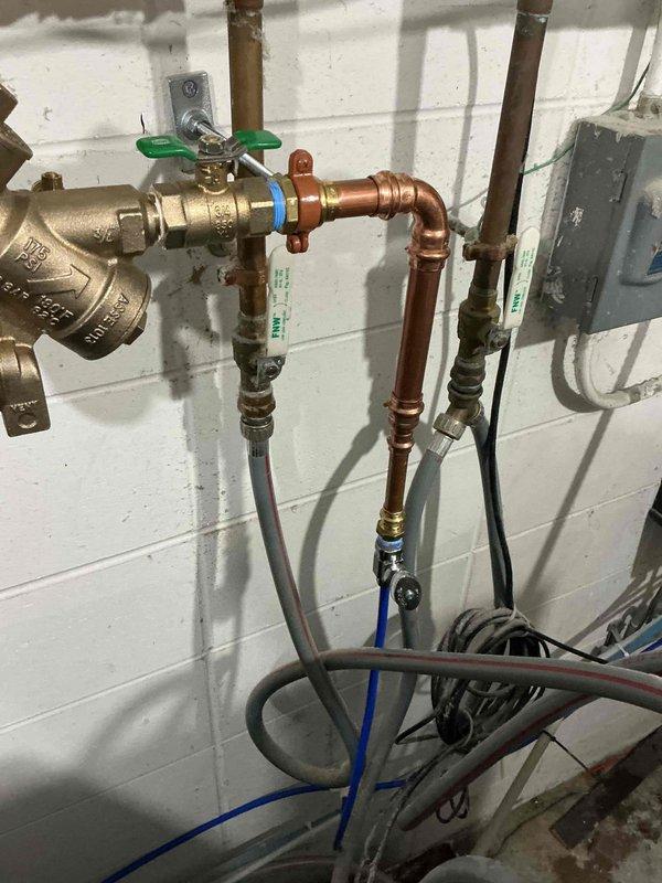 Installed state-approved ASSE 1013 reduced pressure principle backflow preventer to address high hazard cross-connection concerns from laundry detergents and bleach concentrates connected to the potable water system. The RPZ assembly was required to pass cross-connection control inspection and includes brass valves, copper piping, Y-strainer, and test cocks mounted on utility room wall. Device has been registered and will require annual testing by an approved cross-connection control specialist to maintain compliance.