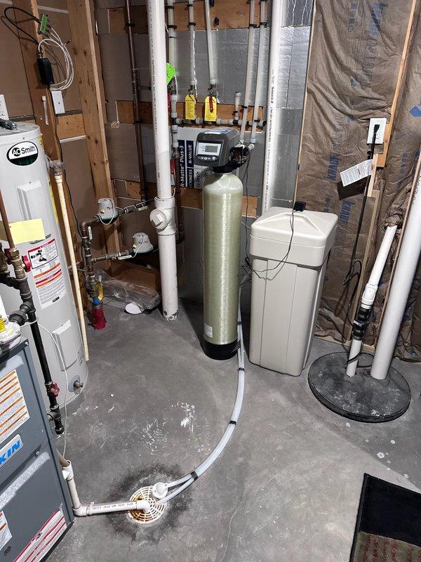 Responded to low water pressure complaint affecting the upper level of a 10-year-old residence. Upon arrival, confirmed that water pressure issues occurred only when the water softener was in service, with normal pressure restored when the system was bypassed. Performed diagnostic testing on the water softener system and identified that the softener control head was malfunctioning and not fully shifting during regeneration cycles, restricting water flow and causing reduced pressure throughout the upper level plumbing fixtures. The control head's failure to complete proper valve positioning prevented water from passing through the system at full volume. Provided estimate for replacement of the defective softener control head and complete resin bed replacement to restore proper system operation and water pressure. Documented equipment condition with photographs showing the existing water softener tank, brine tank, control head assembly, and associated plumbing connections. Submitted serv