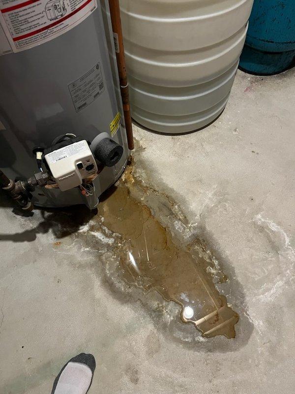 Responded to no hot water call and found severely corroded tanked water heater actively leaking from top of unit, with extensive water pooling on basement floor. Removed failed water heater and installed new replacement unit. Replaced corroded gas tire fitting above water heater during installation to ensure safe gas connection. System tested and restored to full operation with hot water service confirmed.