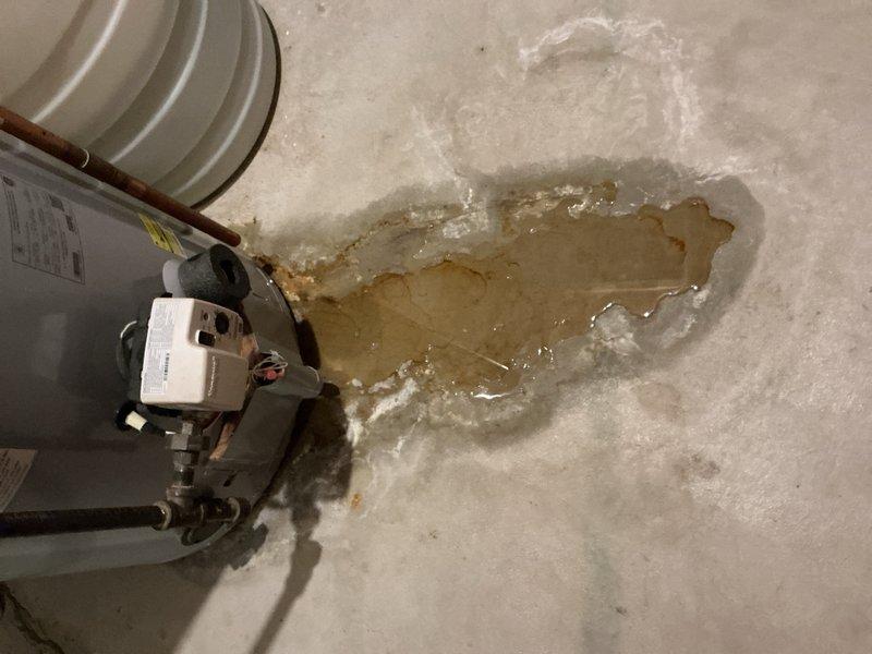 Responded to no hot water call and found severely corroded tanked water heater actively leaking from top of unit, with extensive water pooling on basement floor. Removed failed water heater and installed new replacement unit. Replaced corroded gas tire fitting above water heater during installation to ensure safe gas connection. System tested and restored to full operation with hot water service confirmed.
