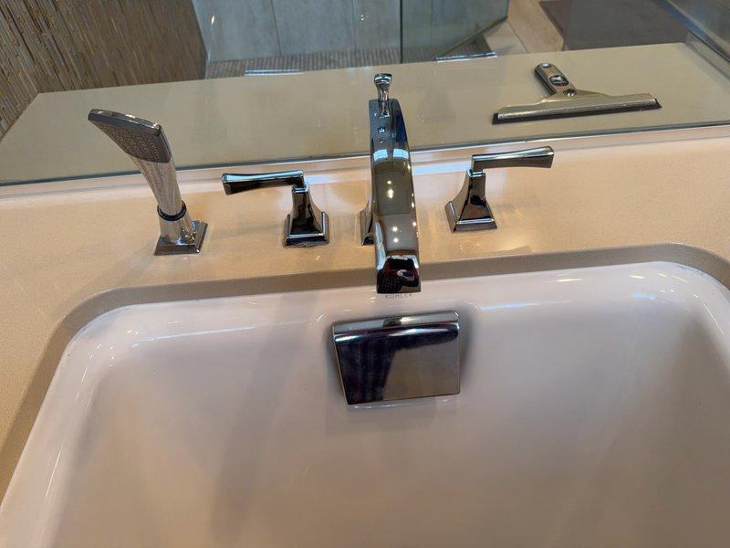 Responded to a bathtub spray hose control mechanism stuck in the off position. Upon inspection, diagnosed a seized diverter on the deck-mounted tub faucet assembly. Attempted to access the diverter mechanism but determined there was no access panel or opening underneath the deck for repair. Due to the permanent installation and lack of access, advised that the tile grout lines surrounding the faucet would need to be cut to remove and replace the entire faucet assembly. Presented repair proposal to replace the deck-mounted tub faucet, which was accepted, with the understanding that a contractor would need to perform the tile work to provide necessary access for faucet replacement.
