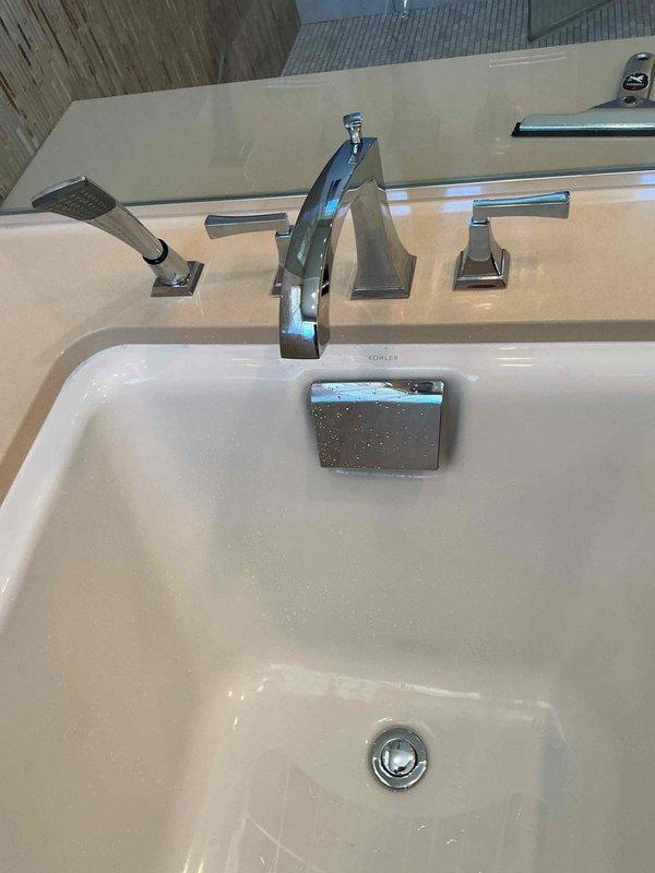 Responded to a bathtub spray hose control mechanism stuck in the off position. Upon inspection, diagnosed a seized diverter on the deck-mounted tub faucet assembly. Attempted to access the diverter mechanism but determined there was no access panel or opening underneath the deck for repair. Due to the permanent installation and lack of access, advised that the tile grout lines surrounding the faucet would need to be cut to remove and replace the entire faucet assembly. Presented repair proposal to replace the deck-mounted tub faucet, which was accepted, with the understanding that a contractor would need to perform the tile work to provide necessary access for faucet replacement.