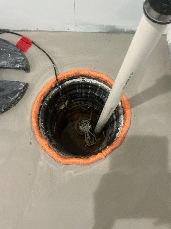 Responded to emergency service call for smoking sump pump in owner-occupied residential property. Upon inspection, determined complete sump pump failure, likely caused by obstruction at the drainfield preventing proper drainage. Removed failed pump unit from sump pit and cleared basin of debris. Installed new sump pump assembly with appropriate discharge piping, secured vertical PVC discharge line to wall corner with mounting straps, and verified proper sealing of floor penetration with gasket ring. Tested new pump operation to confirm proper cycling and drainage functionality. Customer approved replacement solution and installation was completed successfully.