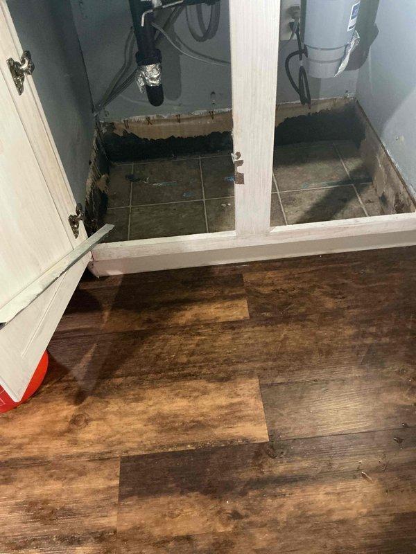 Responded to emergency call for massive leak under kitchen sink. Upon inspection, identified defective fixture stop as source of leak, which had caused significant water damage to flooring and utility room walls. Replaced faulty fixture stop to stop active leak and prevent further damage. Also provided estimate for water heater replacement as requested by homeowner. Documented existing water damage to laminate flooring and utility room baseboards with photographs for insurance purposes.