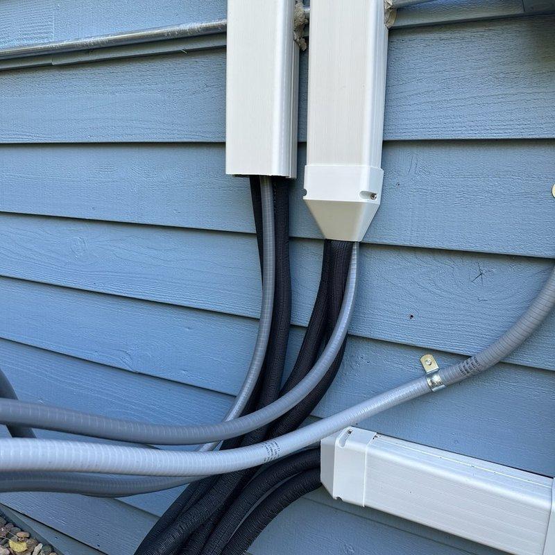 Returned to address two inspection failures on recent Mitsubishi Electric mini-split installation. Installed missing end cap on refrigerant line hide cover to meet code requirements. Investigated reported oily liquid leak on outdoor heat pump unit by operating system and performing thorough inspection of refrigerant lines and connections. Determined wet spot was normal condensation on refrigerant line, not oil or refrigerant leak. Verified system operation with indoor head unit running, confirmed no signs of oil residue or refrigerant leakage present. System operating properly and ready for re-inspection.