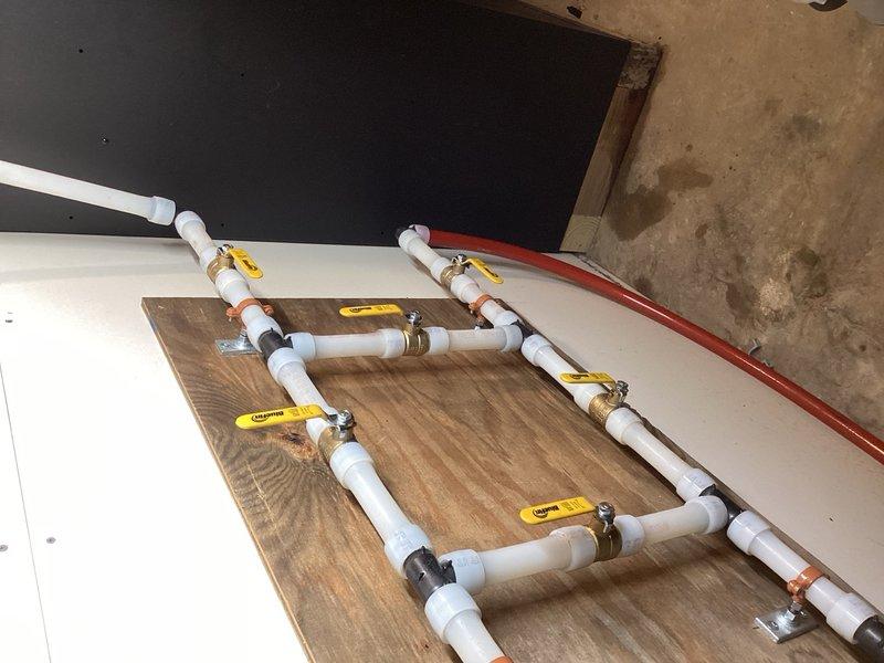 # Boiler System Re-Piping

Completed comprehensive re-piping of both indoor and outdoor boiler systems. Installed new PVC manifold distribution system with multiple zone controls, featuring yellow-handled ball valves at each branch for individual flow management. Mounted entire assembly on wooden backing board with proper support and secured all connections with appropriate PVC and brass fittings for long-term reliability.