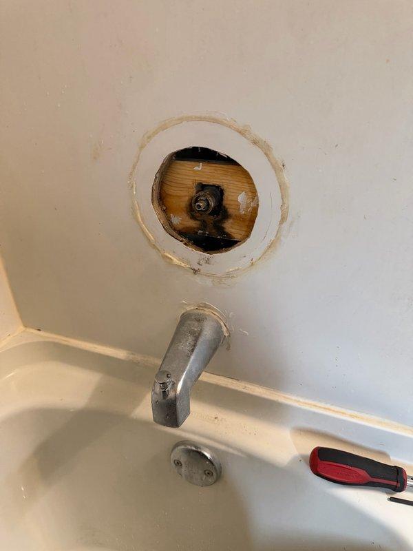 Responded to service call for shower leak and clogged sink. Upon inspection, identified leaking shower valve at cartridge port and backed-up downstairs vanity drain with leaking drain assembly. Attempted extraction of old Moen cartridge, but cartridge was seized and would not move. Determined full shower valve replacement necessary. Provided estimates for shower valve replacement and vanity drain repair. Photographed existing conditions showing stained vanity sink with dual-handle faucet and compromised drain assembly, as well as tub/shower access point with exposed valve assembly behind wall. Ordered required parts for valve replacement and scheduled return visit to complete installation upon parts arrival.
