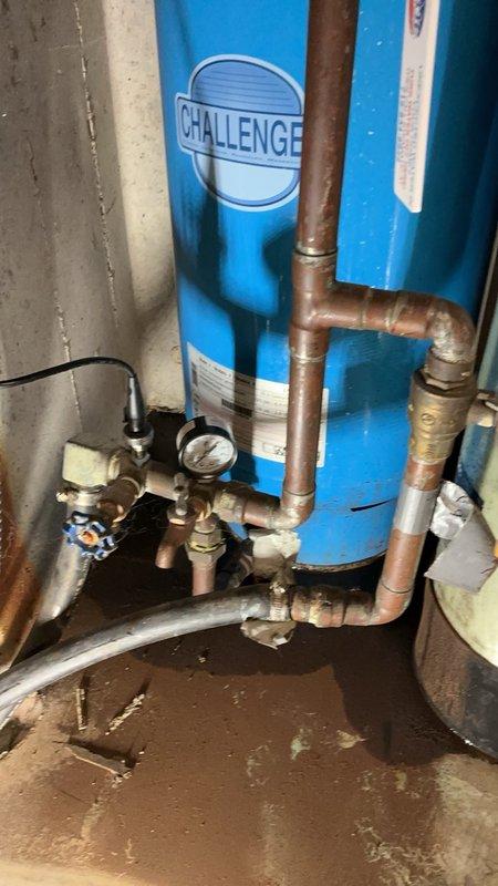 Responded to emergency call for leaking pressure tank system. Upon inspection, found 33.4 gallon Challenger PC122R pressure tank had rusted out and was actively leaking. Additionally discovered the elbow fitting beneath the tank had ruptured, contributing to water damage on the concrete floor. Removed the failed pressure tank and ruptured elbow assembly. Installed new 33.4 gallon Challenger PC122R pressure tank with new connections to existing copper piping system. Verified all fittings were secure and tested system for proper pressure and operation. System restored to full functionality with no additional leaks detected.