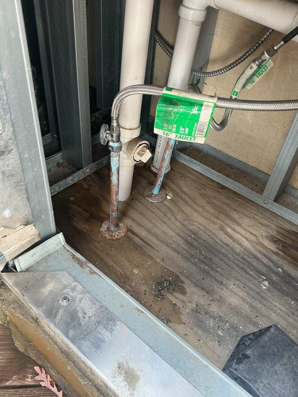 Responded to service call for outdoor faucet experiencing seasonal leaking and two indoor faucets with suspected cartridge failures. Replaced outdoor spigot assembly mounted on exterior wall, including installation of new brass valve body with cross-handle and connection to existing flexible braided supply line via adapter fittings. Addressed water intrusion issues affecting the mounting area on white wooden trim. Inspected and serviced interior plumbing connections in utility access area, working with PVC supply lines and flexible braided hoses connected to wooden platform assembly. All connections tested for proper operation and leak-free performance upon completion.