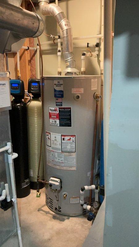 Completed comprehensive plumbing system inspection including water heater, water softener/filtration system, and kitchen plumbing fixtures. Inspected gas water heater with proper venting and pipe connections, verified operational status of dual water treatment tanks with digital controls, and examined kitchen sink faucet with pull-down sprayer for proper function and absence of leaks. All systems found to be in good working condition with no visible signs of corrosion, leaks, or required repairs at time of inspection.