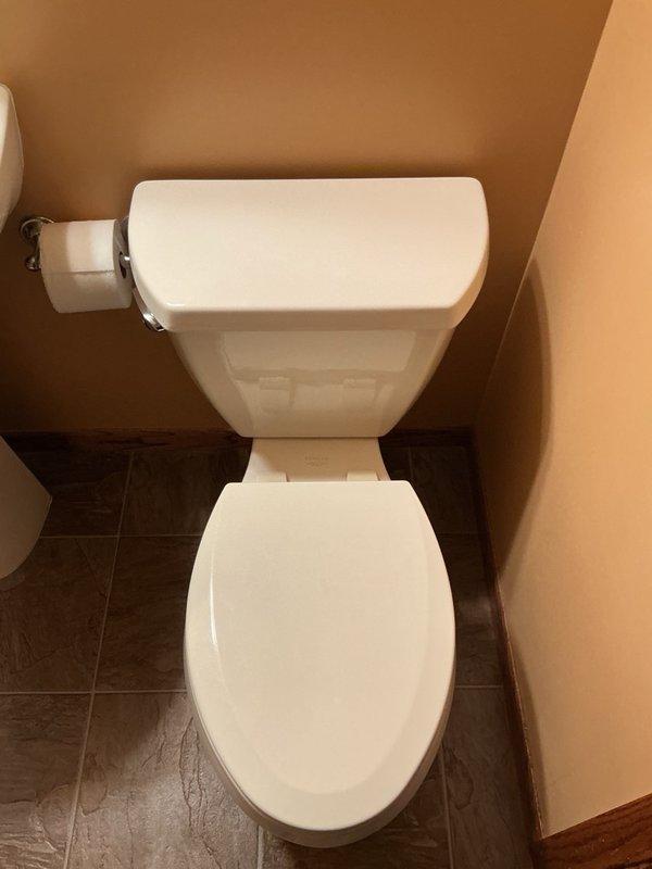 Responded to service call for two malfunctioning Kohler toilets in residence. Diagnosed and repaired leak on basement toilet caused by improperly secured tank-to-bowl bolt that was less than hand tight; tightened bolt to proper torque specification to eliminate leak. Inspected upstairs toilet with continuous running water issue and determined flush valve had failed and reached end of service life; noted significant sediment accumulation in tank affecting performance. Replaced defective flush valve assembly on upstairs toilet and restored proper fill and flush operation. Provided estimate for whole house water filtration system to address sediment concerns and prevent future component degradation.