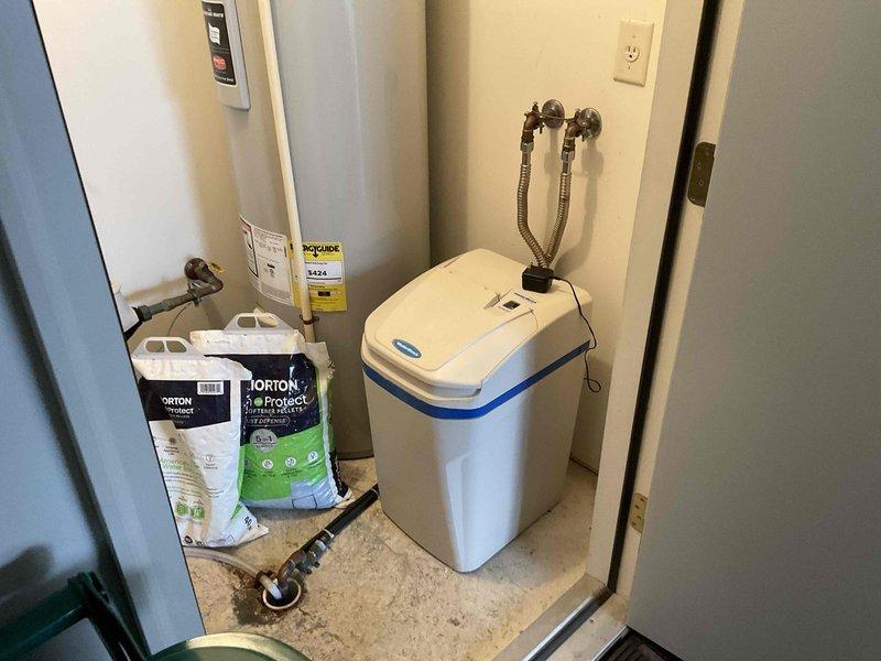 Conducted on-site evaluation of existing water softener system experiencing extended regeneration cycles of approximately 3 hours, indicating potential malfunction or component failure due to age. Assessed current plumbing configuration including wall-mounted supply line connections with braided metal hoses and copper fittings showing oxidation. Inspected mechanical room setup containing water heater and softener unit with dual supply lines. Documented equipment condition and provided bid estimate for water softener replacement to restore proper system operation and reduce excessive cycle times.