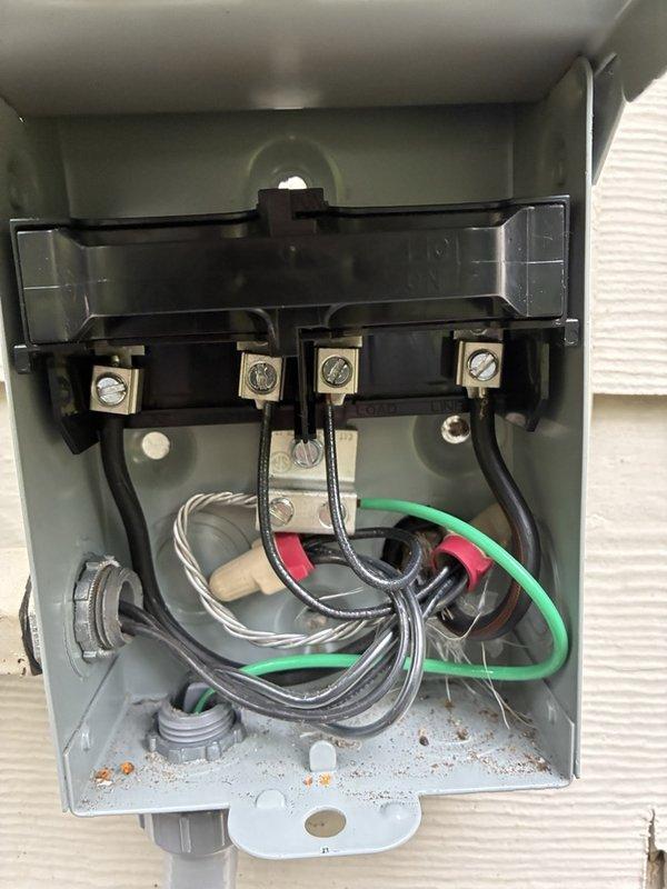 Responded to callback regarding improperly mounted electrical disconnect box on exterior siding. Upon arrival, addressed customer concerns about disconnect installation and discovered significant water damage and deteriorated siding material behind the unit. After consulting with customer, removed disconnect box from wall mounting to allow access for proper flashing installation and siding repair. Disconnect left temporarily suspended by electrical whip to maintain power while customer completes necessary flashing work behind box location. Customer will reinstall disconnect upon completion of weatherproofing repairs. Documented existing conditions including exposed underlayment damage, deteriorated wall board, and compromised siding integrity around mounting area.