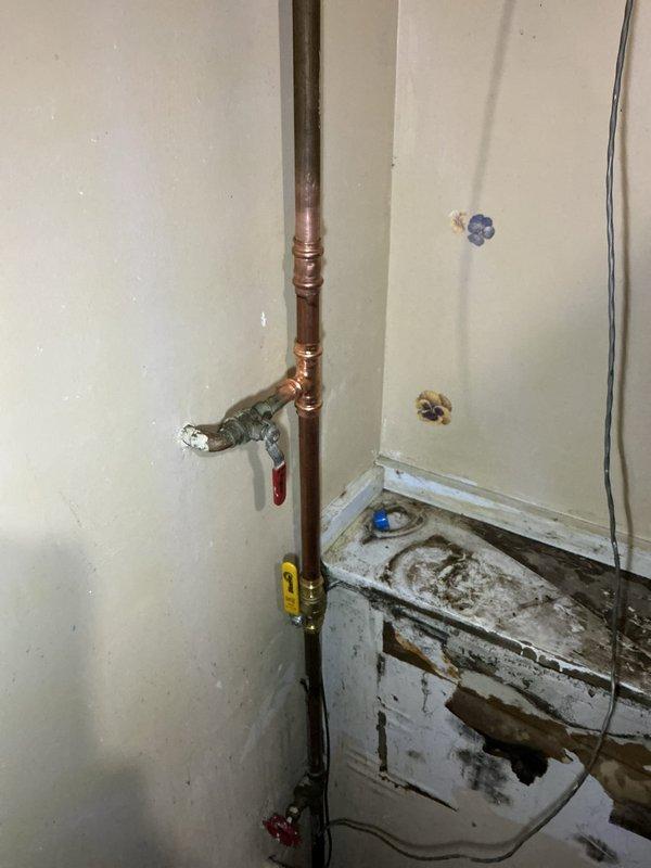 Responded to emergency water leak caused by laundry tub detaching from wall, resulting in broken supply pipes near the main water valve. Disconnected damaged laundry tub connections and restored main house water supply by reconnecting and securing copper piping infrastructure. Customer also reported natural gas water heater not heating properly; preliminarily assessed heating element as likely cause of malfunction in 8+ year old unit requiring further evaluation or replacement.