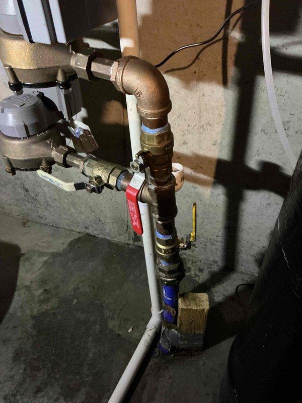 Responded to emergency water main leak at owner-occupied residential property built in 2021. Upon arrival, coordinated with River Falls utility company to shut off water at the curb stop, as the home had no water supply due to a failed ball valve. Inspection revealed the main isolation ball valve serving the entire home had split and required immediate replacement.

Removed the damaged ball valve assembly and installed a new brass ball valve with red handle to serve as the primary whole-home shutoff. Utilized proper thread seal tape on all connection points to ensure leak-free joints. Connected the new valve assembly between the existing copper supply line from the water main and the white PVC distribution piping serving the residence. Installed appropriate brass fittings and elbows to maintain proper configuration and flow direction.

After installation was complete, coordinated with River Falls to restore water service at the curb stop. Tested the new ball valve for proper operation 