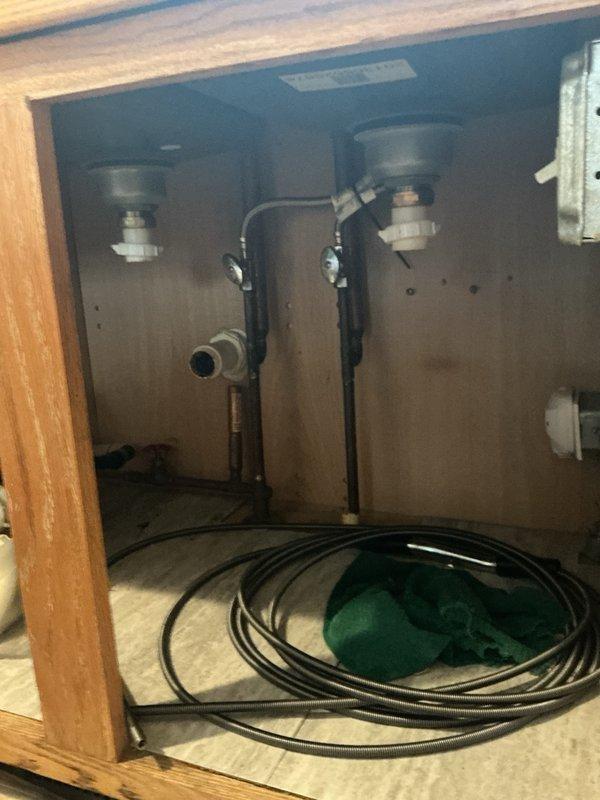 Responded to a main line drain stoppage affecting the kitchen sink and dishwasher. Upon inspection, discovered the sink drain was clogged with an accumulation of hair and grease buildup causing water to back up and prevent proper drainage. Utilized a drain snake to clear the obstruction from the line, restoring full flow and drainage capability to both the kitchen sink and dishwasher.