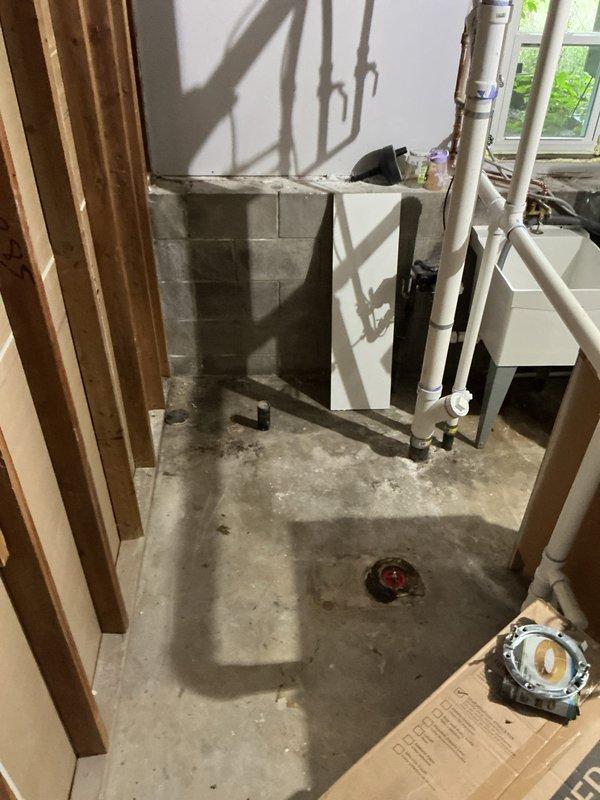 Returned to complete basement toilet installation after fixture became available. Repaired corroded and damaged toilet flange in concrete floor. Installed new water supply line by teeing off existing plumbing, including shut-off valve and supply line connection. Successfully set and secured toilet to restored flange.