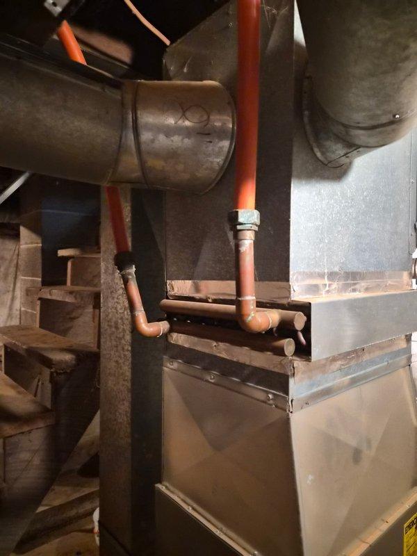 Disconnected and removed outdoor woodstove piping that had been previously connected to the LP gas furnace by the prior homeowner. Cut and capped the piping inside the mechanical room to safely isolate the woodstove from the gas furnace system, with the homeowner responsible for removing the external components. Documented the work with photos showing the furnace, ductwork, and disconnected piping configuration.