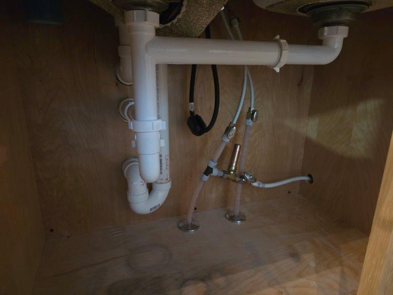 Responded to a kitchen sink drain leak with water gushing from failed glue seams and running through cupboards into the basement. Upon inspection, identified a leaking and partially clogged P-trap as the primary source of the water intrusion. Removed the defective P-trap assembly and installed a new PVC P-trap with proper connections and seals. Cleared the partial blockage by running a drain cleaning machine through the line to ensure proper flow. Tested the entire drainage system by running a full dishwasher cycle, verifying no leaks at connections and confirming proper drainage function. All plumbing connections secured and water-tight upon completion.
