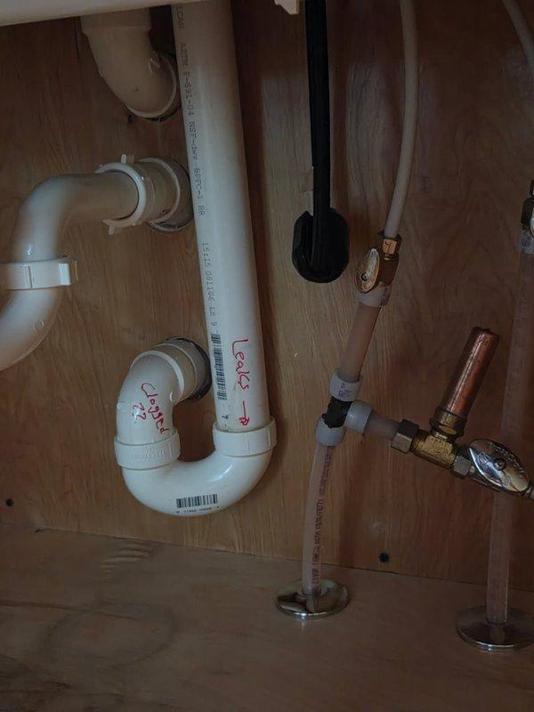 Responded to a kitchen sink drain leak with water gushing from failed glue seams and running through cupboards into the basement. Upon inspection, identified a leaking and partially clogged P-trap as the primary source of the water intrusion. Removed the defective P-trap assembly and installed a new PVC P-trap with proper connections and seals. Cleared the partial blockage by running a drain cleaning machine through the line to ensure proper flow. Tested the entire drainage system by running a full dishwasher cycle, verifying no leaks at connections and confirming proper drainage function. All plumbing connections secured and water-tight upon completion.