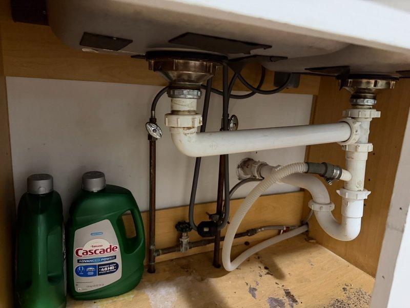 Responded to service call for intermittent water leak under kitchen sink. Upon inspection, found faulty continuous waste drain connections between double sink basins that were separating and causing leakage. Replaced existing PVC drain piping assembly including P-trap configuration and connection points. Secured all pipe connections with proper clamps to prevent future separation. Tested system for proper drainage and verified no leaks present at all connection points.
